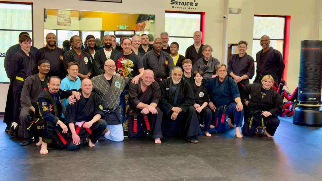 Large group of Burning Tree MMA adult students and instructors posing together on the gym mat
