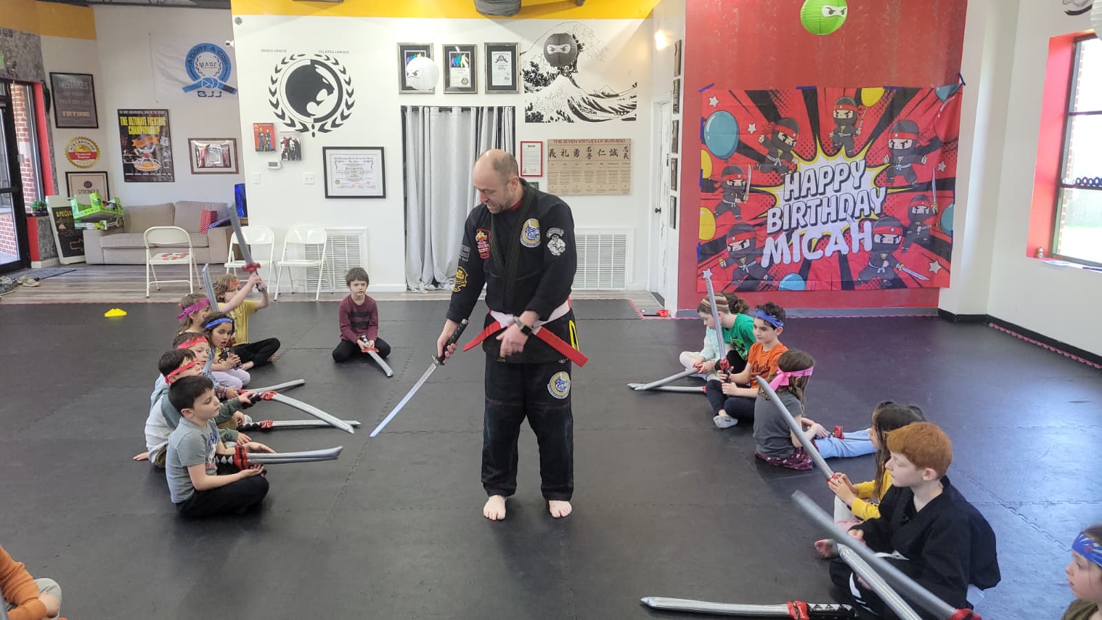 Instructor leading children in a foam sword activity at a martial arts birthday party