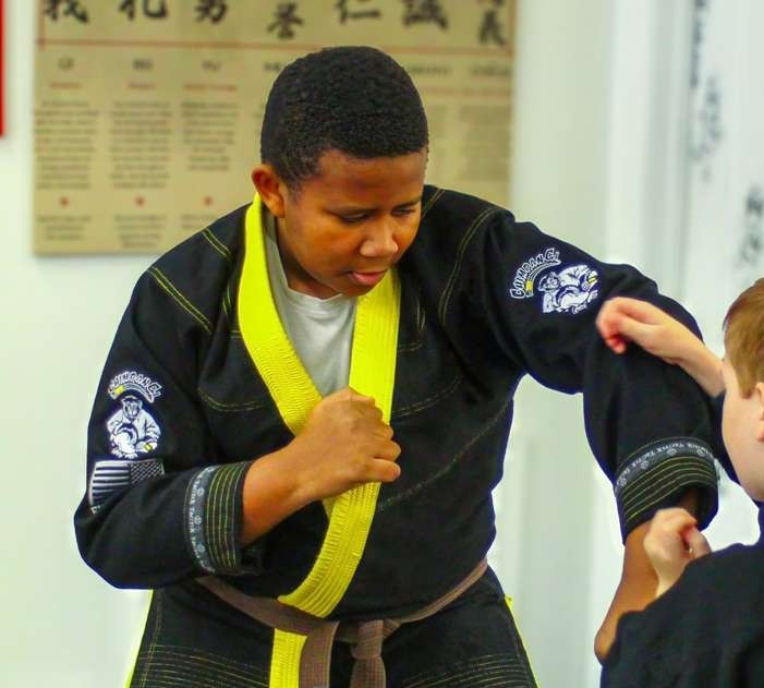 BJJ practitioners in gis training a throwing technique during live grappling with an American flag in the background