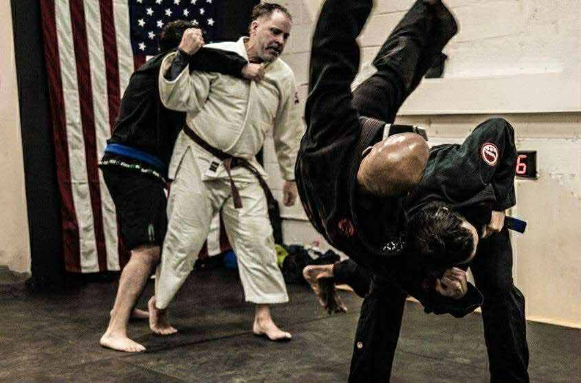 Martial arts students practicing technique during live training with an American flag in the background