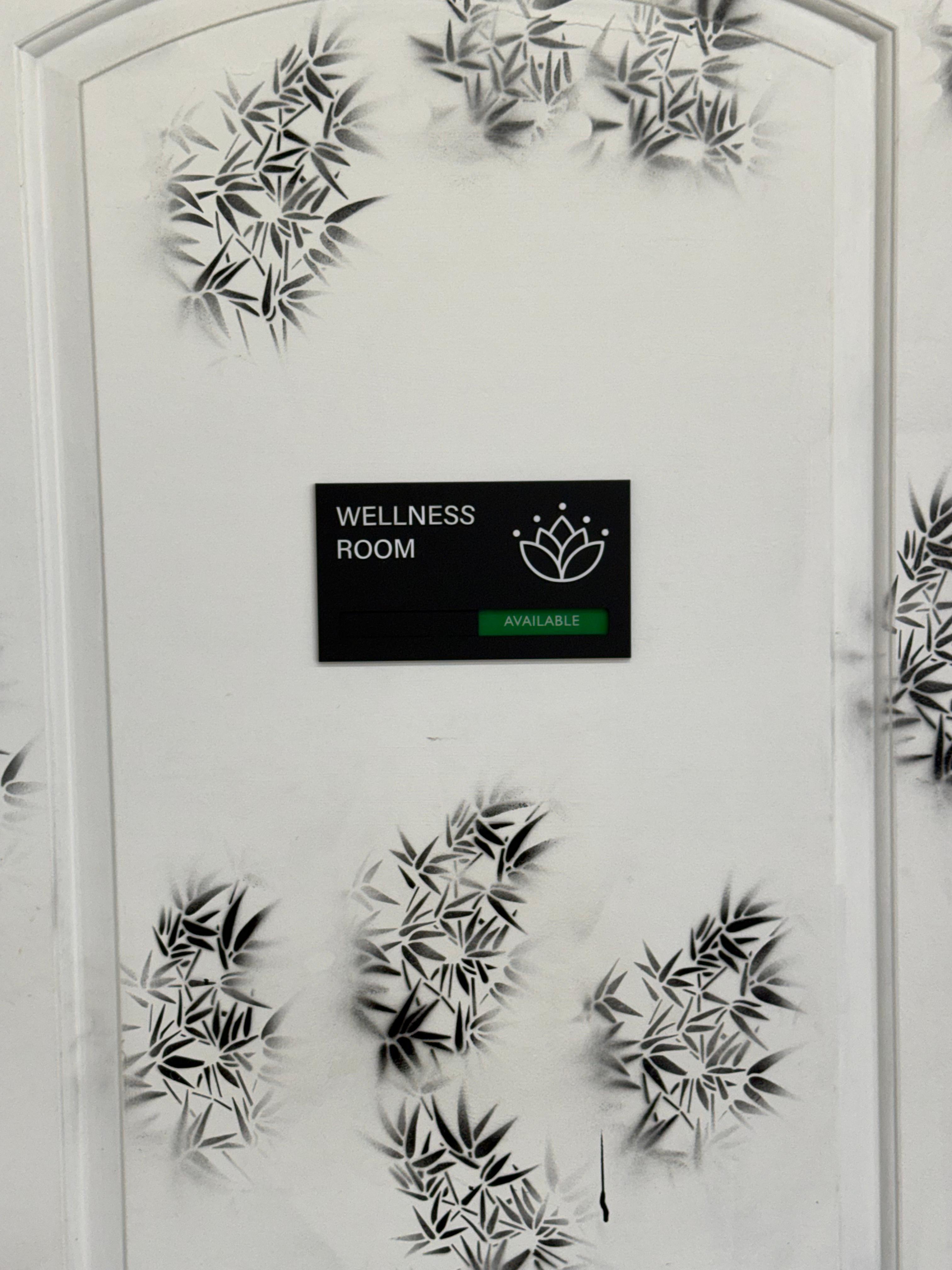 Wellness Room door with bamboo leaf stencil artwork and an Available digital sign