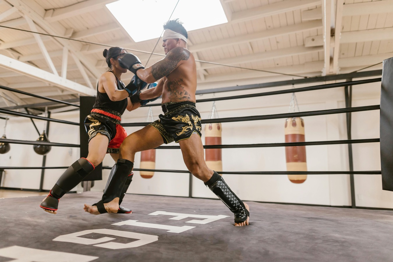 Two Muay Thai students in full protective gear practicing a kick technique during class