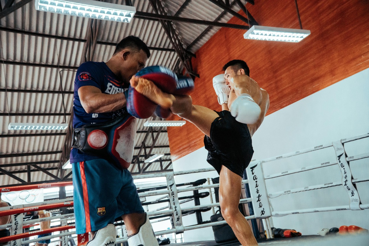 Two men in black training clothes practicing a striking combination in the gym, black and white photo