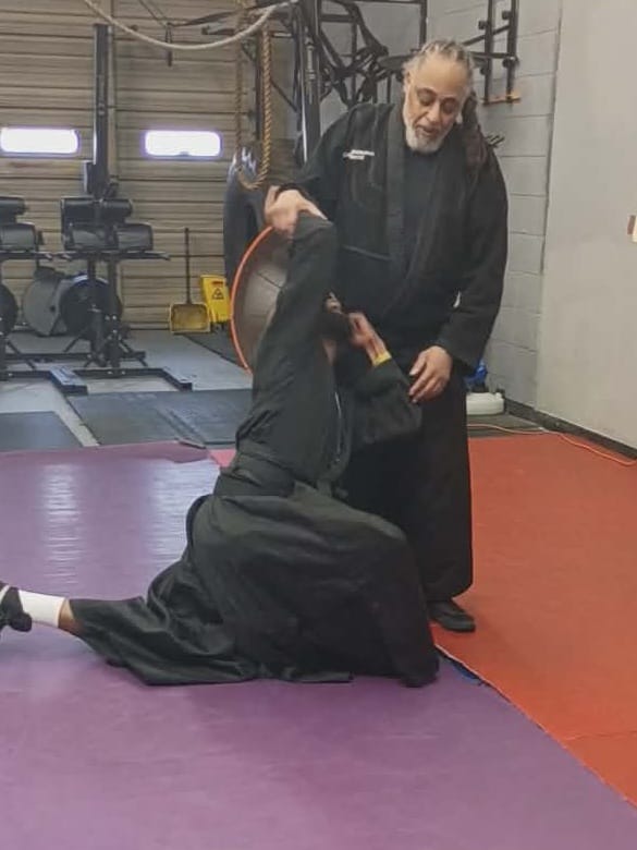 Women's self-defense students practicing ground defense at Burning Tree MMA in Owings Mills